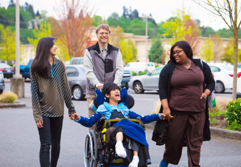 three person walking and one person in a wheelchair