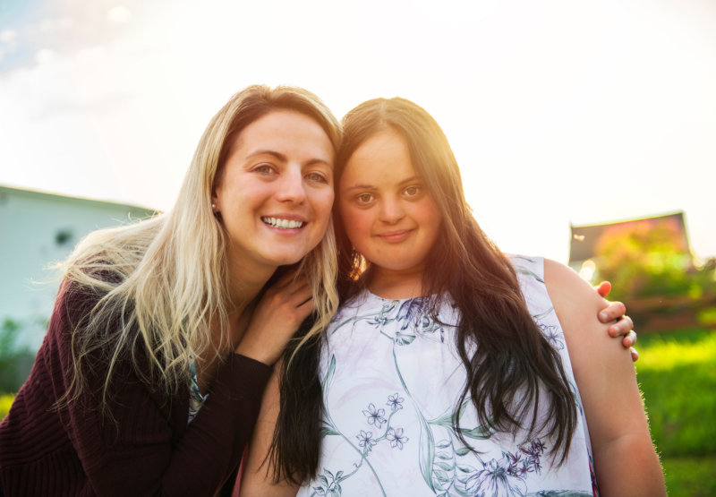 21 adult girl smilin outside at sunset with family friend
